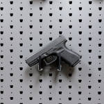 Horizontal pistol hanger mounted on GallowTech wall panel holding a handgun in a straight-on view