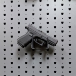 Hybrid Handgun Hanger Right holding a handgun, straight-on view on Gallow wall panel