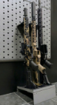 Hybrid vertical stock floor shelf holding three rifles, left angle view