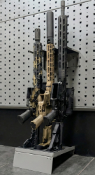 Hybrid vertical stock floor shelf holding three rifles, installed with wall-mounted installation bar