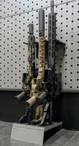 Hybrid vertical stock floor shelf holding three rifles, installed with wall-mounted installation bar